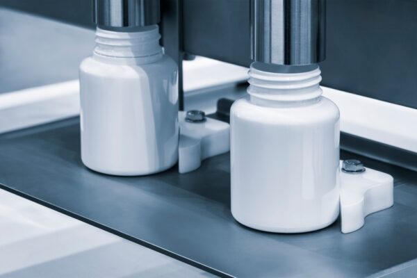 medicine pills are filling in the bottle on production line machine conveyor