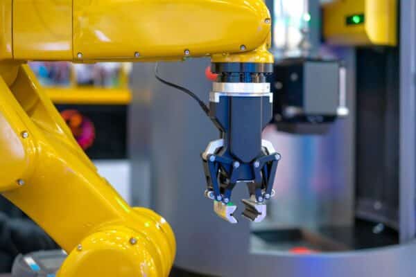 A close-up of a yellow robotic arm with a precision gripper